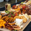 table covered by assortment of food such as meats, cheeses, nuts, fruits, and vegetables.