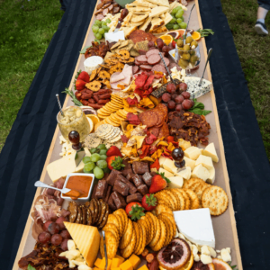 table covered by assortment of food such as meats, cheeses, nuts, fruits, and vegetables.
