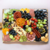 Large board with an assortment of fruits, meats, cheeses and veggies.