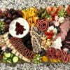 Charcuterie board with assortment of meats, cheeses, fruits, and vegetables.