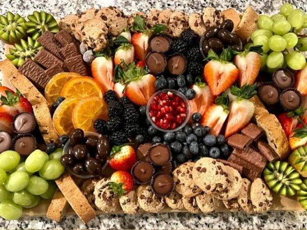 Board in fruitopia and sweet tooth style which is assorted fruits and chocolates.
