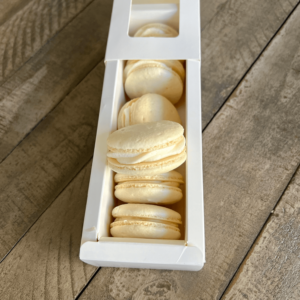 Vanilla macarons in a box with one on top